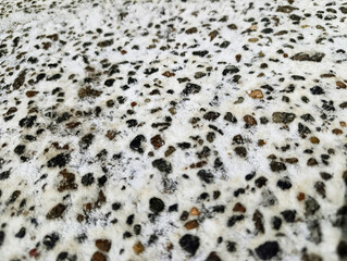 The texture of asphalt covered with snow, with small stones