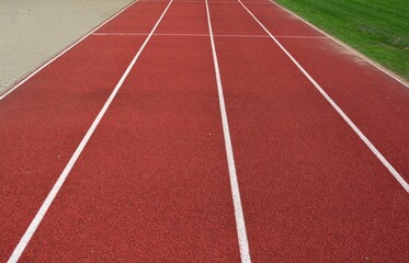 Red running track with white lines, footpath in left side and green grass in right side