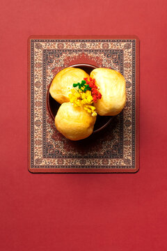 Kazakh baursaks on a decorative plate. Golden fried dough pieces with a soft texture. Garnished with colorful flowers. Traditional dish for Nauryz.