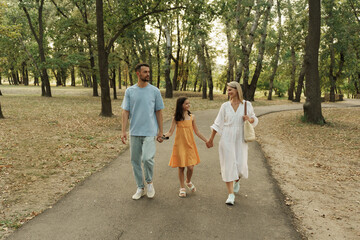 Smiling family enjoys a relaxing walk on a tree-lined path.