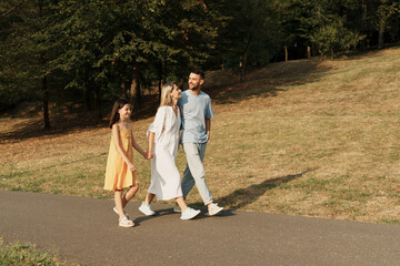 Fototapeta premium Happy family walking in the park on a sunny day, enjoying nature.