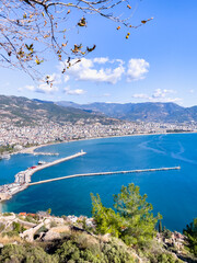 Panoramic view of a stunning coastline featuring turquoise waters, mountains, and a vibrant town