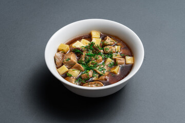 Savory vegetable and meat stew served in a white bowl on a dark background highlighting the delicious ingredients