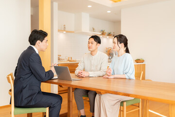 スーツ姿のビジネスマンに営業を受ける夫婦