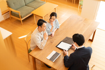 スーツ姿のビジネスマンに営業を受ける夫婦