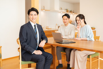 スーツ姿のビジネスマンに営業を受ける夫婦