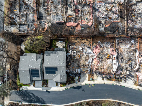 Aerial view of the Eaton Fire destruction in Altadena, California, showing entire neighborhoods devastated by wildfire alongside surviving homes and streets