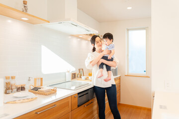 1歳の男の子を抱いて家事する若い母親 © folyphoto