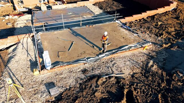 Aerial futage of an site engineer land surveyor using total station to check accuracy and position of foundation for new house 