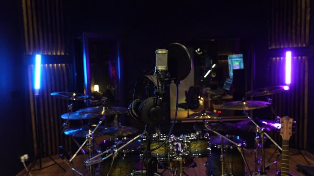 Professional recording studio setup featuring a drum kit, microphone, and headphones, ready for a music session