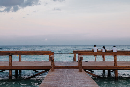 People enjoying a serene sunset on a wooden pier in Tulum