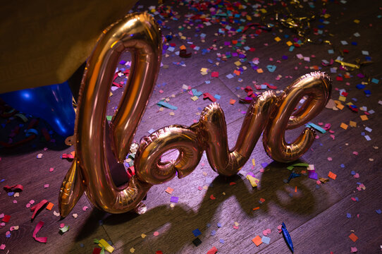 Metallic love balloon on vibrant confetti-covered floor