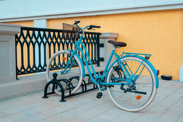 Obraz premium Blue classic city bike standing in bicycle parking lot in front of yellow apartment building