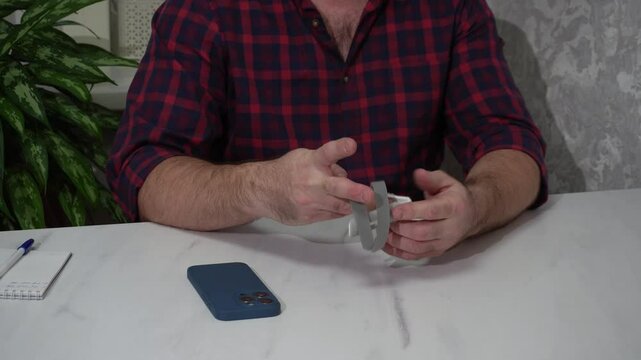 A man removes a recovery splint from his finger, a medical fixation device that ensures an inflexible position for the finger.