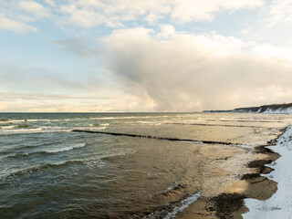 Winter Beach Landscape With Snow and Waves Under a Cloudy Sky in the Late Afternoon