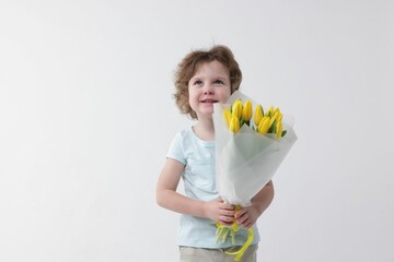 Cute little boy with bouquet of tulips on white background
