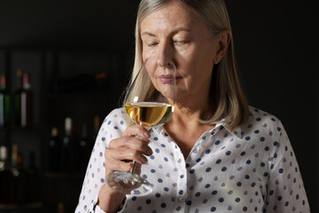 Professional sommelier tasting white wine in glass indoors