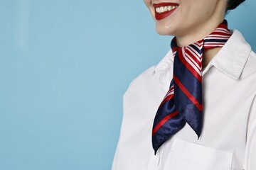 Smiling flight attendant on light blue background, closeup. Space for text