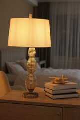 Obraz premium Beautiful night lamp, stack of books and airplane model on chest of drawers in bedroom