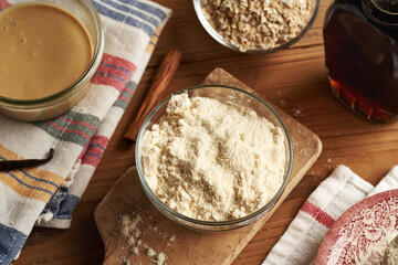 Whey protein powder, sesame tahini, oat flakes, maple syrup and cinnamon - ingredients for homemade no-bake protein bars