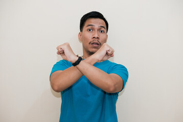 A Southeast Asian man in a turquoise green tshirt smiling and making an 