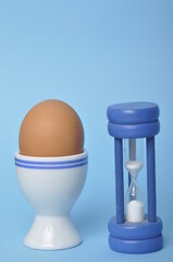 Boiled egg and hourglass on a blue background