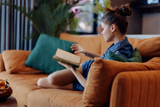 Cozy relaxing moment at home woman reading book while enjoying coffee on orange couch
