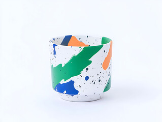 Obraz premium White cup with splashes of blue green and orange paint set against a plain white background.