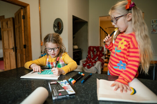Two sisters drawing at the kitchen island