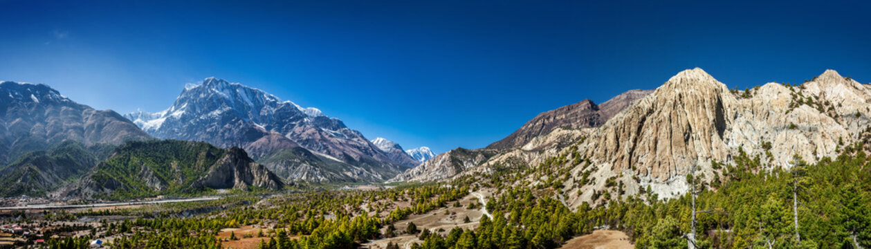 Wide panoramic view of the Marsyangdi river valley. Humde village, route to Manang, Annapurna III, Gangapurna, Tilicho peak and sandstone rocks above pine forest on the right. Himalaya, Nepal.