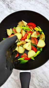 The making of delicious potatoes with tomatoes and onions, on frying pan