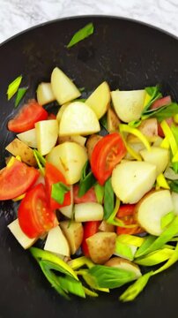 The making of delicious potatoes with tomatoes and onions, on frying pan