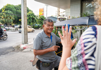 Thai tuk tuk driver interacts with an anonymous female tourist in Chiang Rai