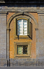 Fototapeta premium Open window with wooden shades on old building brick wall facade