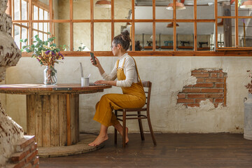 Young woman teleworking in a rustic style cafe