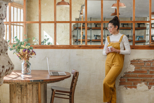Female entrepreneur teleworking in stylish rustic cafe