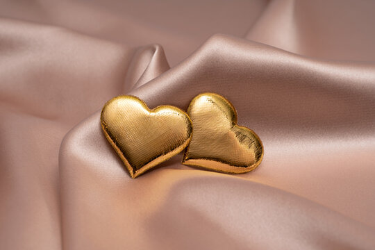 Golden hearts on silky fabric for St. Valentine's Day and weddings