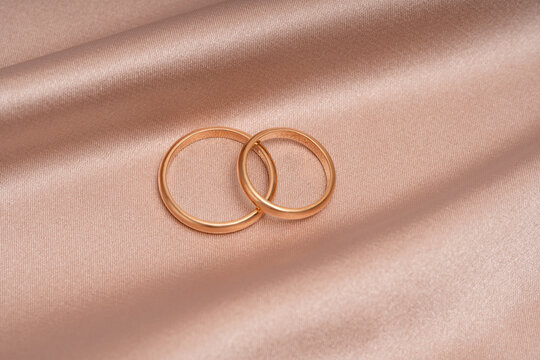 Elegant gold wedding rings on a silky pink fabric