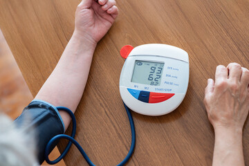 Blood pressure monitor checking health at home on wooden desk