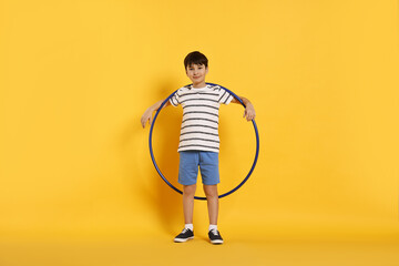 Boy with hula hoop on yellow background