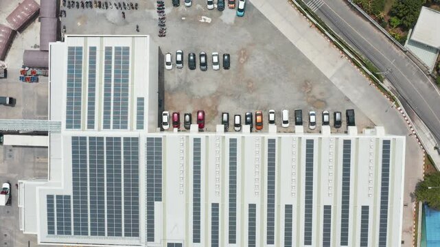 Top down footage isolates parallel solar panel strips across white mall roof. Parked cars border photovoltaic modules, emphasizing geometric layout and commercial renewable power generation.