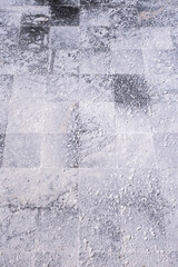 close-up of the bottom of a salt evaporation pond covered in salt residue. The textured surface showcases crystallized salt formations and natural patterns in shades of white and gray