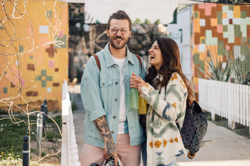 Portrait of happy hipster couple with juice bottles having fun on street