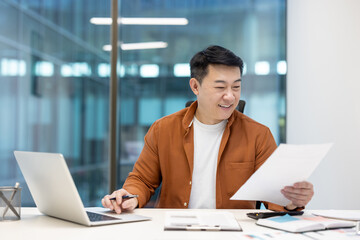 Successful joyful businessman investor doing paperwork, asian man working with documents reports...