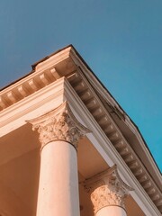 Fototapeta premium Round beige stone columns support the roof of a building on a summer day