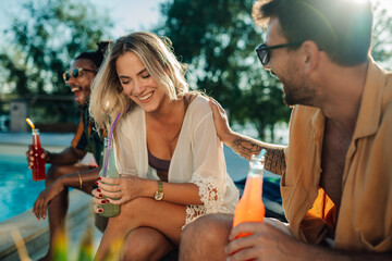 Friends enjoying drinks by the pool during summer vacation