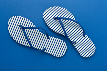 Striped blue flip-flops on color background, top view