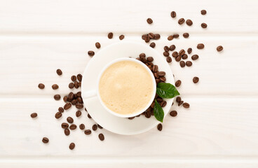 Cup of coffee with coffee beans and leaves on wooden background,top view
