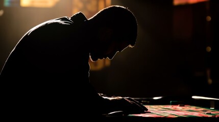  Silhouette of focused gambler contemplating roulette table in dimly lit casino setting for high-stakes gaming mood