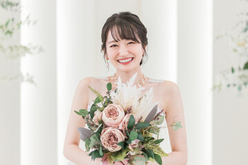 結婚式場でブーケを持つ花嫁・新婦の女性（笑顔）
